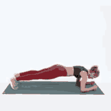 a woman is doing a plank on a yoga mat with her legs crossed .