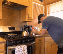 a man in a blue shirt is standing in front of a stove that says ' stainless steel ' on the top