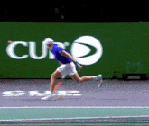 a man in a blue shirt and white shorts is running on a tennis court in front of a curb sign