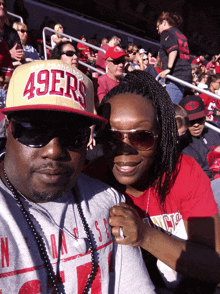 a man in a 49ers hat sits next to a woman in a red shirt