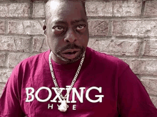 a man wearing a boxing hype t-shirt is standing in front of a brick wall