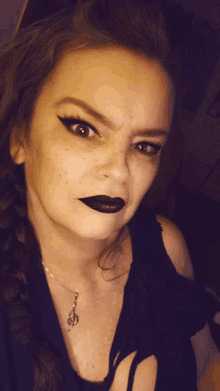 a woman wearing black lipstick and a necklace with a treble clef pendant