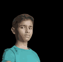 a young boy in a blue shirt is looking at the camera with a black background