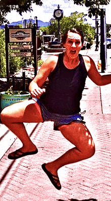 a woman is squatting on the sidewalk in front of a sign that says " downtown santa fe "