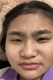 a close up of a girl 's face with a purple sweater