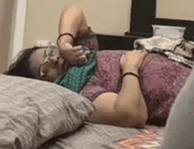 a woman is laying on her stomach on a bed holding a glass of water .