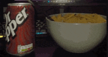 a can of dr pepper sits next to a bowl of nachos