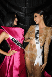 two women are posing for a picture and one has a sash that says singapore