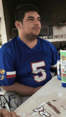 a man wearing a number 5 jersey sits at a table