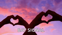 a couple of hands making a heart shape with the words bat signal below them .