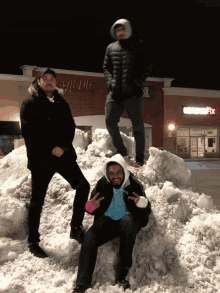 three men standing on top of a pile of snow in front of a store with the word fix on the sign