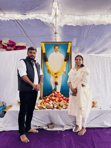 two people stand in front of a painting of a man