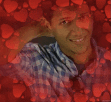 a man in a plaid shirt is surrounded by red hearts and smiling