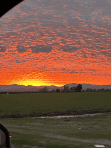 a sunset with mountains in the background and a field in the foreground