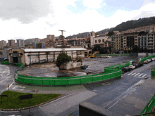 a green fence surrounds a building that has graffiti on the side