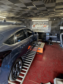 a car is being tuned in a garage with a sign behind it that says custom tuning