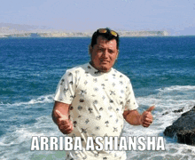 a man is giving a thumbs up while standing on a beach .