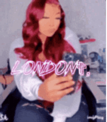 a woman with red hair is taking a selfie with her phone in front of a sign that says london .