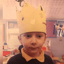 a young boy wearing a yellow crown with a sticker on it that says ' king '