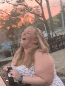 a woman in a white dress is laughing while holding a bottle of beer