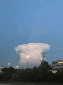 a large cloud in the sky over a city at night