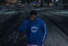 a man wearing a blue hoodie that says gangsta on the sleeve