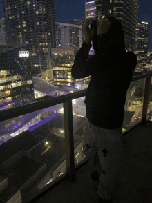 a person standing on a balcony taking a picture of a city skyline