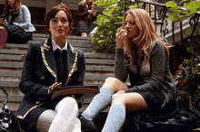 two women are sitting on the steps of a building .