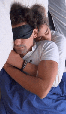 a man with a blindfold on his eyes is sleeping with a woman