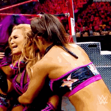 two women are wrestling in a wrestling ring and one is hugging the other .