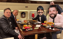 a group of men are sitting around a table with a mcdonald 's hamburger on it