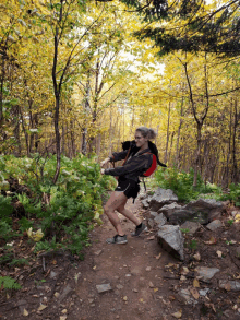 a woman with a backpack is walking down a trail