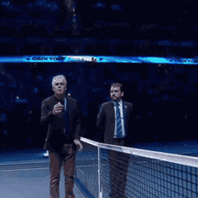 two men are standing on a tennis court with a sign in the background that says ' swiss telecom '