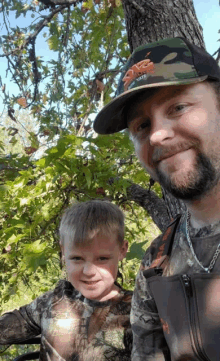 a man wearing a camo hat is standing next to a boy