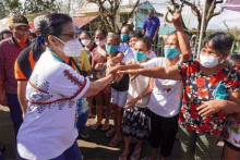 a woman wearing a mask shakes hands with another woman