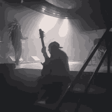 a man playing a guitar on stage in a dark room