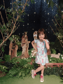 a little girl standing in front of a nativity scene wearing a dress that says barbie on it