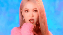 a close up of a woman with long blonde hair wearing a pink sweater .