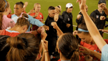 a group of female soccer players are huddled together with their arms in the air and a man wearing a nike hat