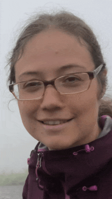 a close up of a woman wearing glasses and a purple jacket