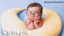 a baby wearing glasses is laying on a yellow crescent moon .