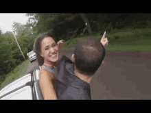 a man and a woman are sitting in the back of a car and the woman is pointing at the camera .