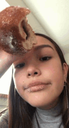 a girl is eating a donut with a bite taken out of it on her face .