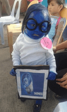 a child dressed as sadness from inside out holding a picture