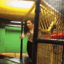 a woman is jumping on a trampoline in a fenced in area