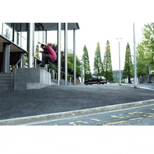 a man in a pink shirt is riding a skateboard on a ramp