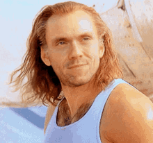 a man with long hair and a beard wearing a blue tank top