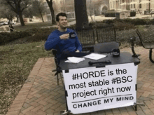 a man sitting at a table with a sign that says horde is the most stable #bsc project right now