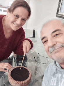 a woman is cutting a cake next to a man who is wearing a shirt that says ' abercrombie & fitch '