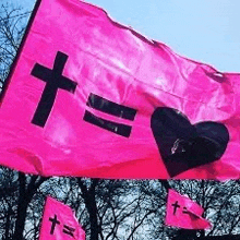 a pink flag with a black cross and a heart on it .